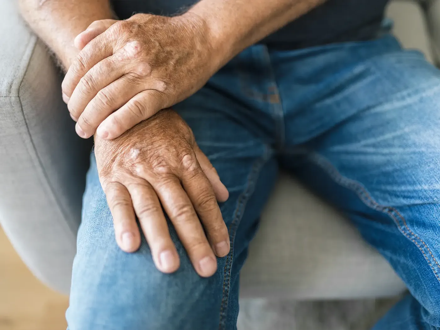 Older adult resting stiff, aching hands on both knees