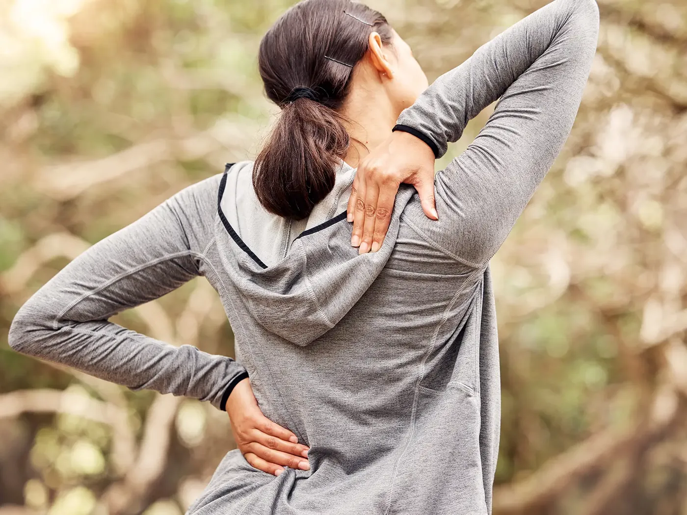 Woman outdoors holding her lower back after activity