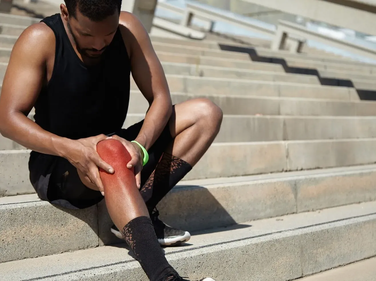 Man stopping on a staircase to hold his knee