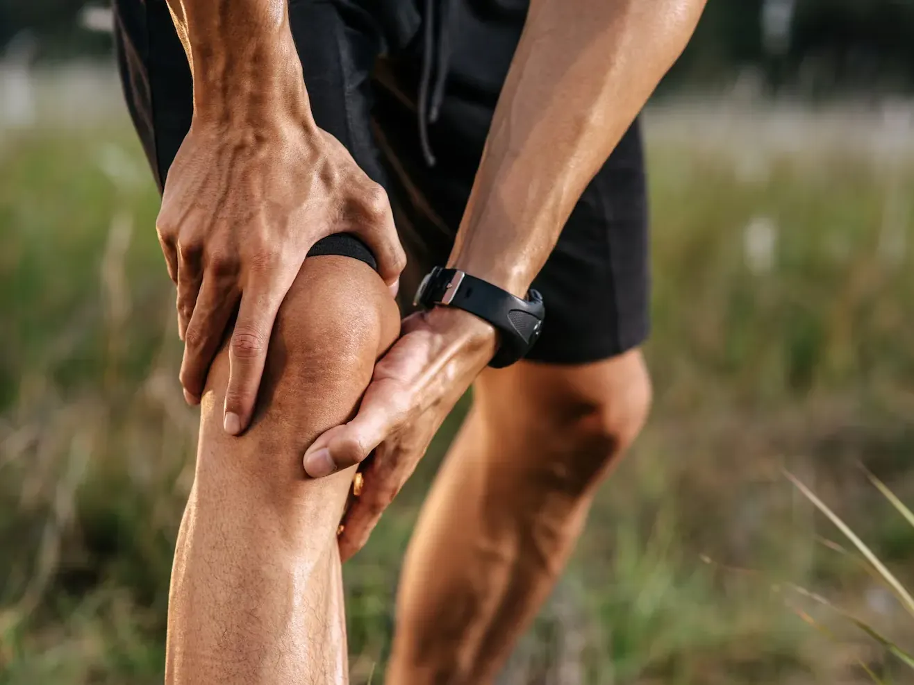 Runner outdoors holding his knee after a run