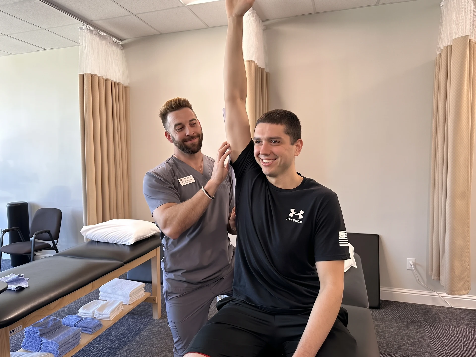 Dr. Ryan Spano guiding a smiling patient through an overhead shoulder stretch at Alpha Physical Therapy in Slidell